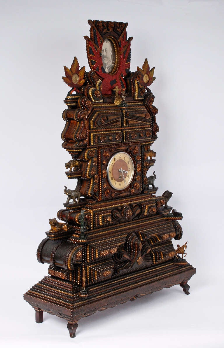 Spectacular tramp art polychrome mantle clock festooned with animals, carved roses, coins in maple leafs and soldiers. An English flag and Union Jack surround a photograph of King George V on its crest. Exhibited at the 1935 Canadian National