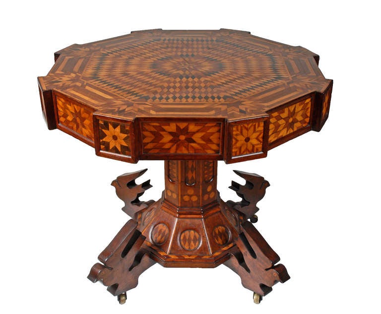 A superb folk marquetry table with carved birds on its base. It is heavily embellished with hundreds of different colored woods meticulously inlaid to form 8 pointed stars and other geometric elements. Circa 1870s.