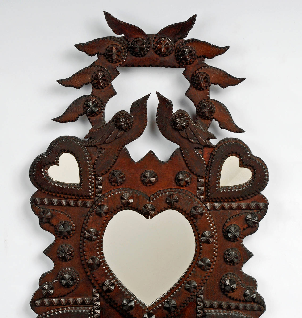 A masterful Tramp Art 'Winged' wall sculpture by John Zadzora. It features his signature styled five heart-shaped mirrors, two drawers and a small compartment. He further embellished his artful wall sculpture with birds, wings and in this rare