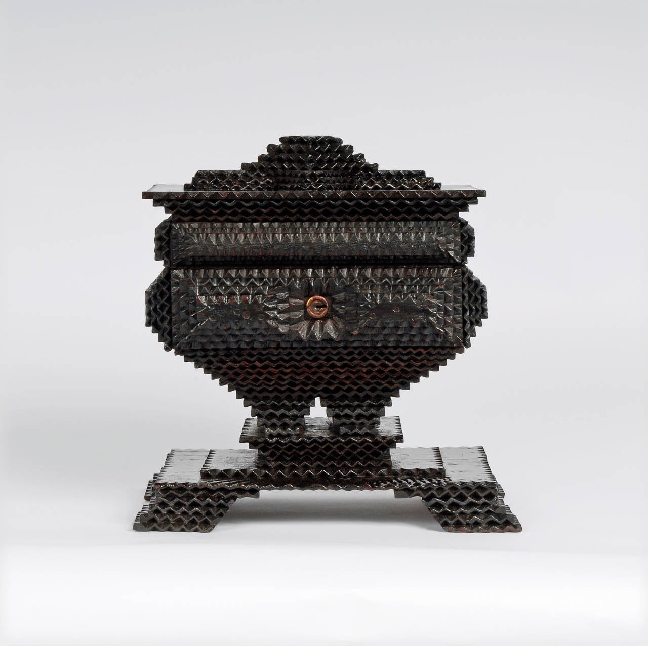 A fine Tramp Art pedestal box on a platform base with splayed legs. Of note is that the artist used several different carving techniques. He used typical chip carving around the central compartment, double-sided or wave notching in other areas (an
