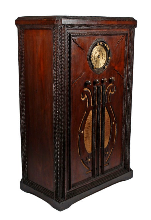 Rare and unique tramp art radio cabinet. Decorated with a cut-out musical lyre on its front and carved lightning bolts. The radio represents a time capsule of American life when the country would ‘watch’ the radio. The handsome radio was from the
