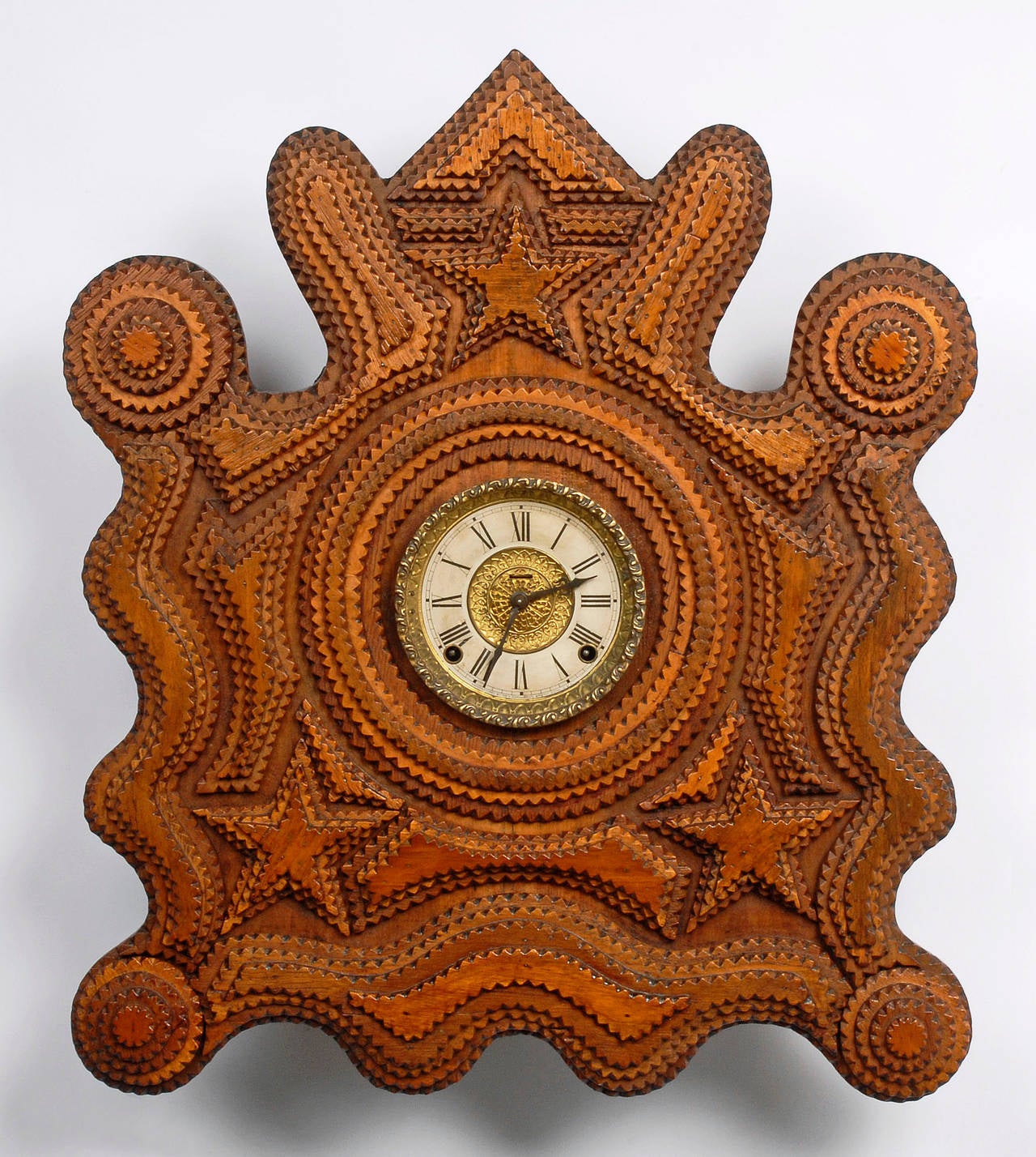 A wonderful and visually striking tramp wall clock with a fluid shape and embellished with stars and rosettes. This clock was illustrated in, Tramp Art a Folk Art Phenomenon, on page 133. It was also exhibited in a Tramp Art show at the Intuit