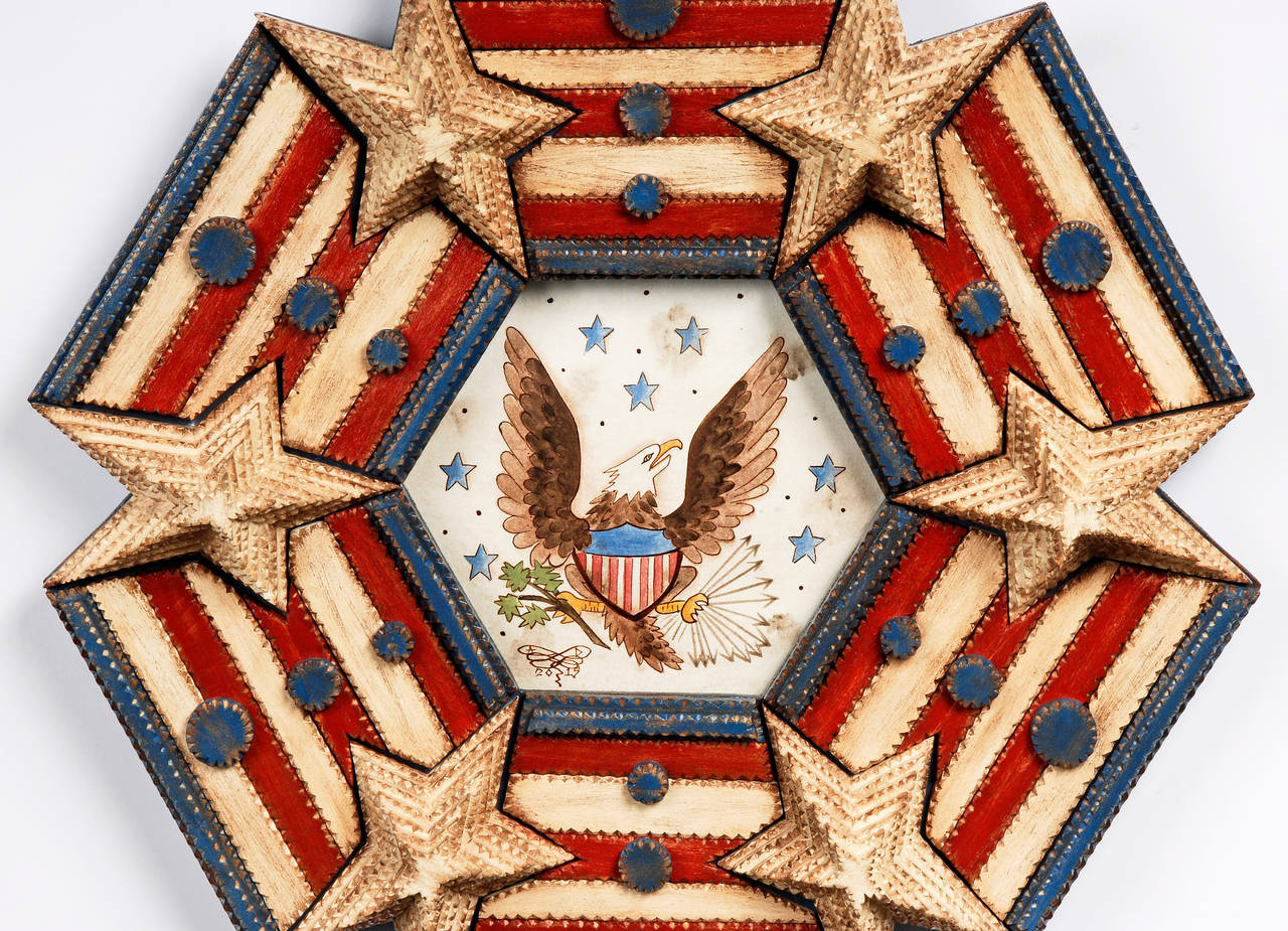 A superb tramp art hexagon shaped ‘Stars and Strips’ frame with a patriotic inspired painting of a wide-spread eagle with the American shield on its chest by noted contemporary artist Angie Dow. Embellished with large deeply layered stars and