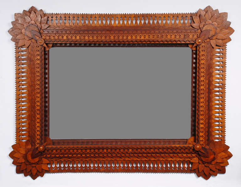 A spectacular and monumental tramp art mirror by esteemed historical tramp artist John Martin Zubersky who lived in Joliet, IL where he made these extraordinary frames. His trademark style combines expressive sunflower corners, deeply layered rows