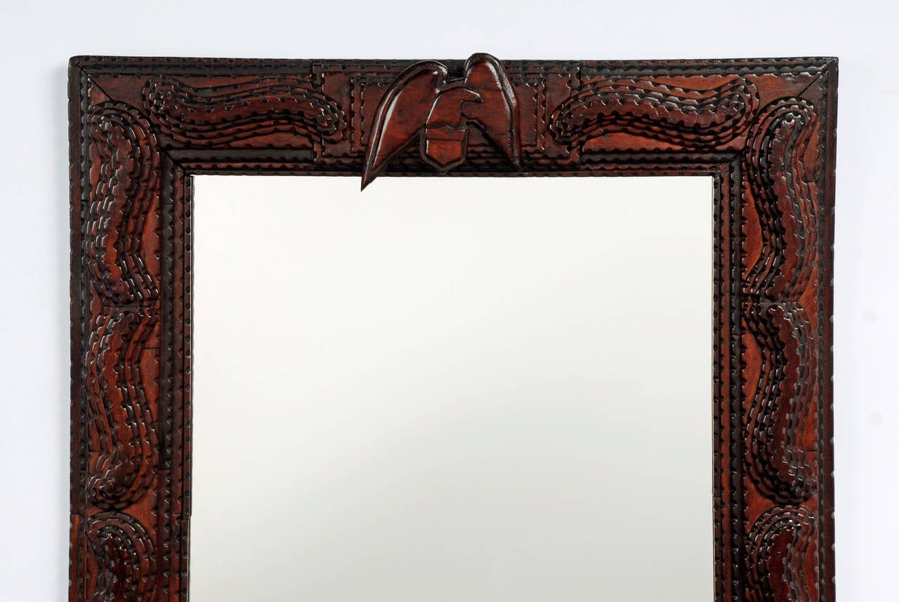 A fine patriotic inspired Tramp Art mirror with a carved eagle and shield. The frame exhibits fluid swirling designs whimsically resembling a Victorian era mustache. Rare symbol of American patriotism expressed in the Tramp Art form.

Found in