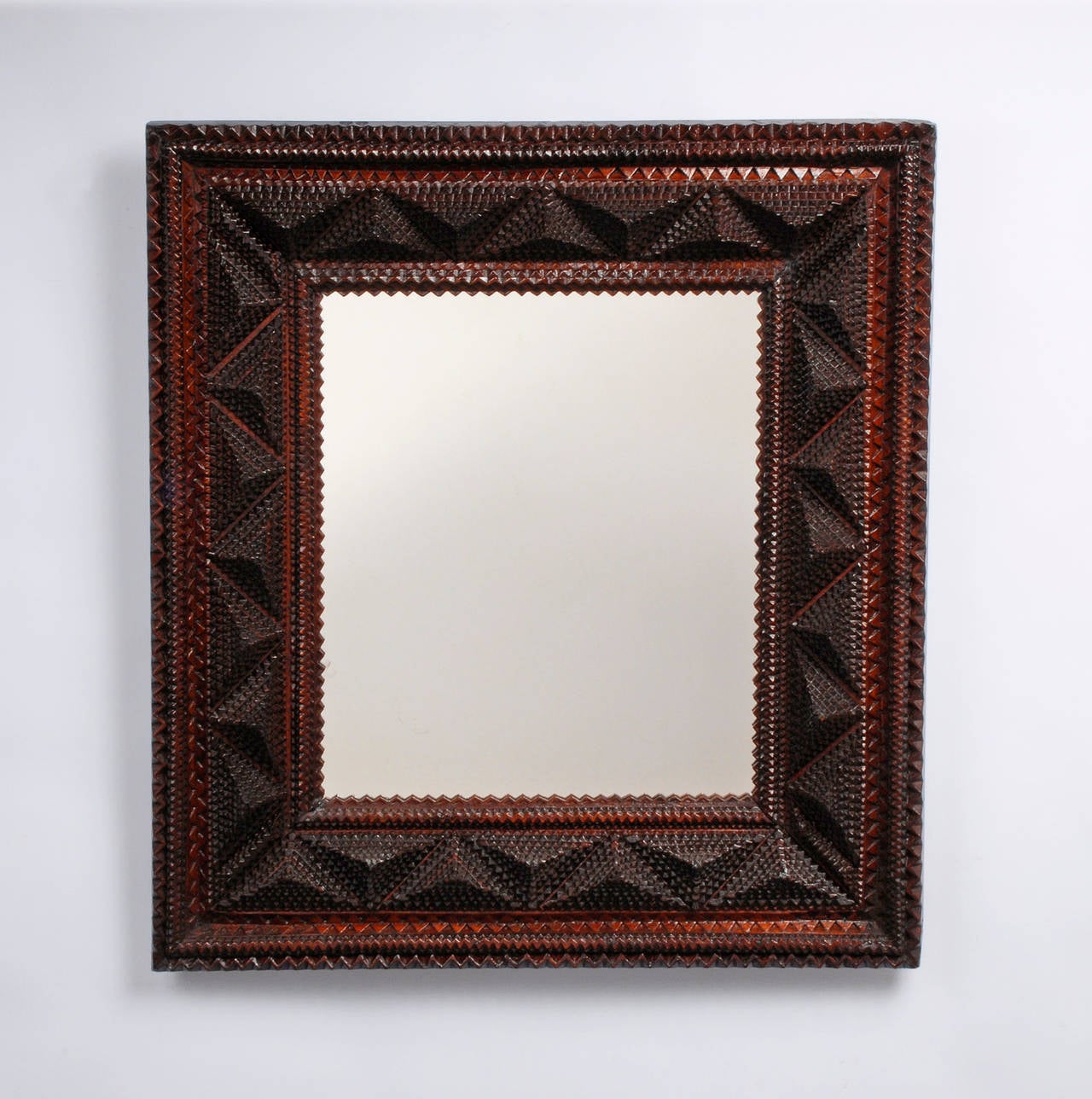 A fine deeply layered tramp art mirror heavily detailed with geometric patterning and a saw-tooth inner border. The frame has a shadow box like appearance with the sides canting forward. 

Circa 1915 - 1925