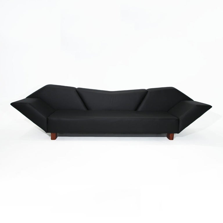 A massive low and geometric sofa by Zanini de Zanine. The sofa is upholstered in black leather. The feet are thick salvaged pieces of Peroba de Campos. Seat depth measures 21.5