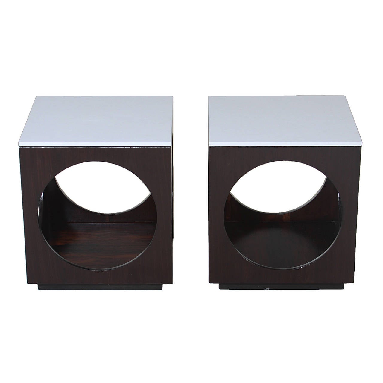 A pair of Brazilian Rosewood and Leather top side tables. The top is upholstered in a white leather and each side of the table has a large cut out circle creating a unique design element. 

Many pieces are stored in our warehouse, so please click