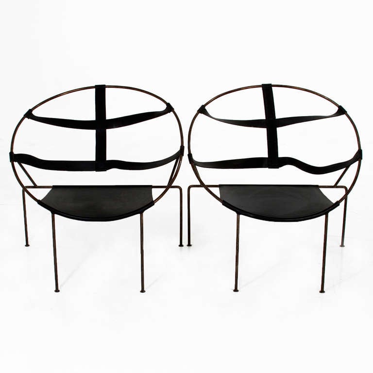 A pair of black leather lounge chairs with angular steel frames. The leather seat is wrapped around the base of the steel frame. The strapped back is divided into four sections. 

Seat Depth= 17