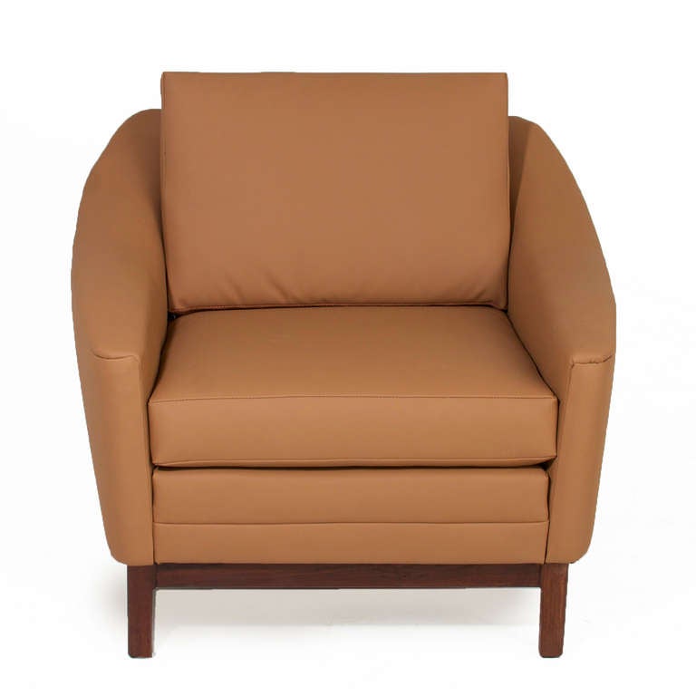 A comfortable tan vinyl armchair with solid walnut base and sloped arms by DUX.

Measures: Seat depth 19