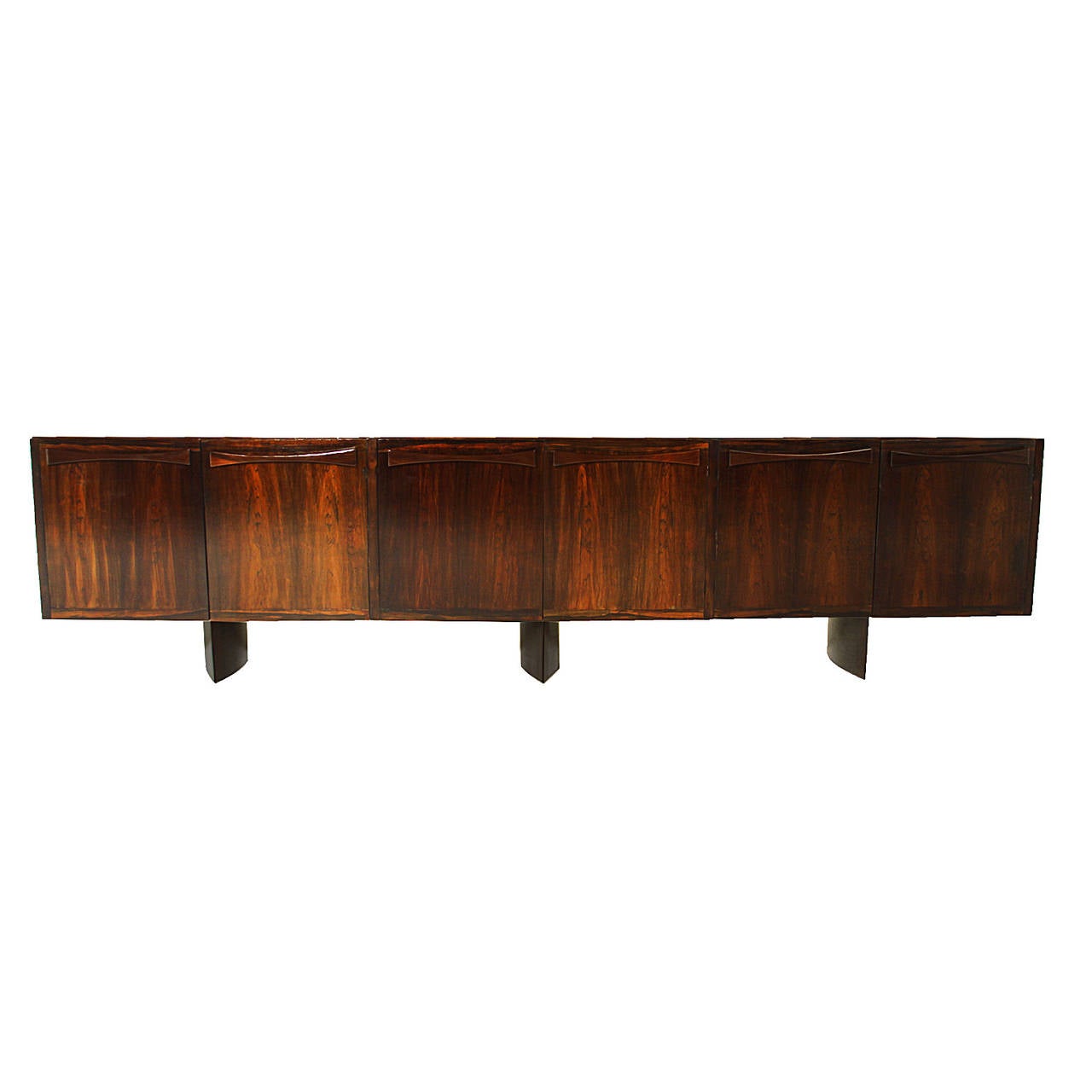 A beautiful rosewood credenza attributed to Jorge Zalszupin. The handles are shaped like bow ties and the feet are eyeball base shaped. These features add a sculptural element to the design.

Many pieces are stored in our warehouse, so please