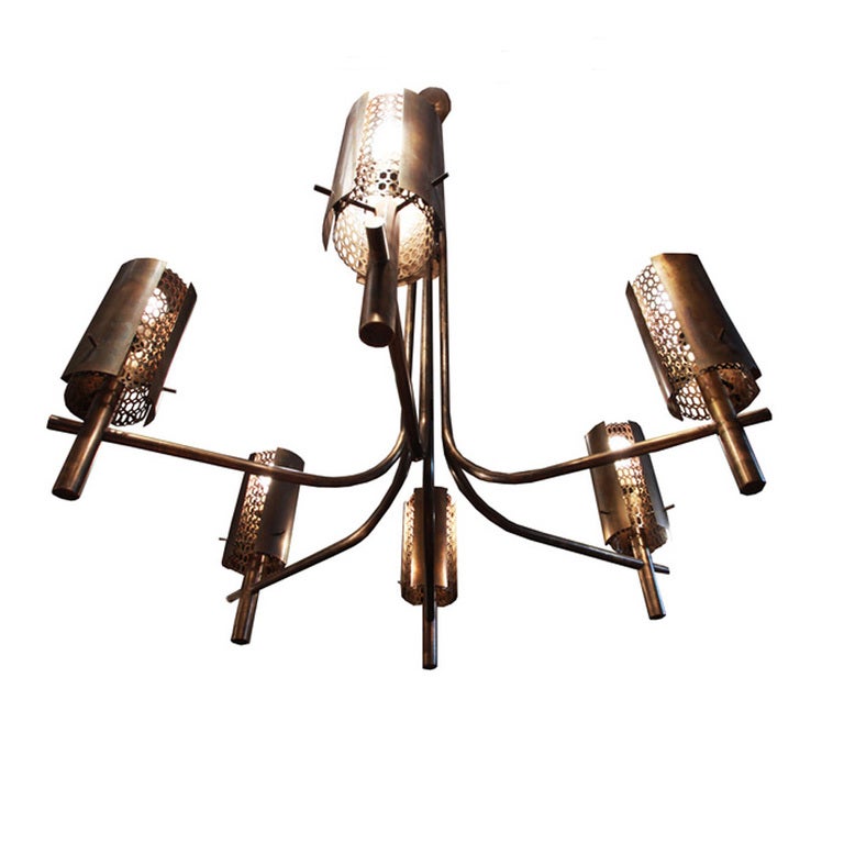 Large bronze chandelier from an opera house in the northwest US. There are six cylindrical fixtures each housing a light bulb that shines through a honeycomb design, throwing beautiful light patterns against the wall. There are five available and