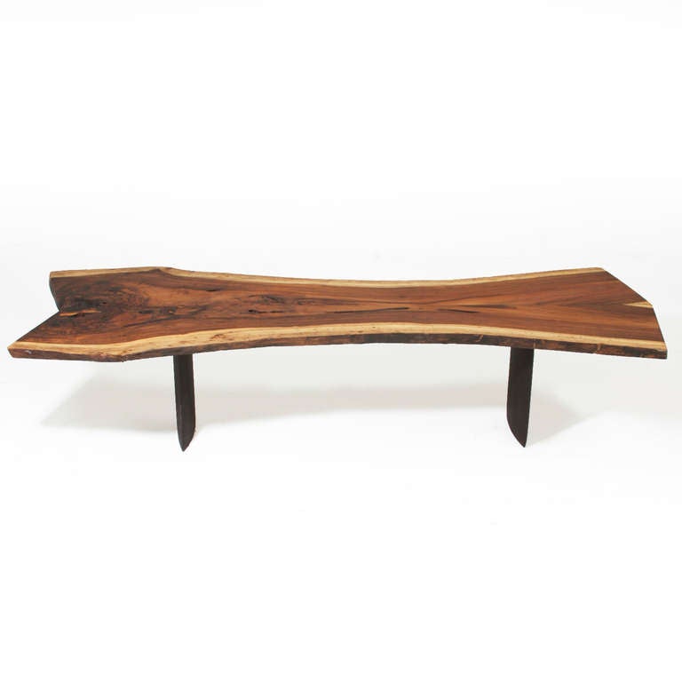 A book matched solid Rosewood slab coffee table with live edges by Thomas Hayes Studio. The Rosewood is salvaged and is from Brazil, and has significant blonde sap grain along the edges. The double pedestal bases are solid ebonized Mahogany. The top