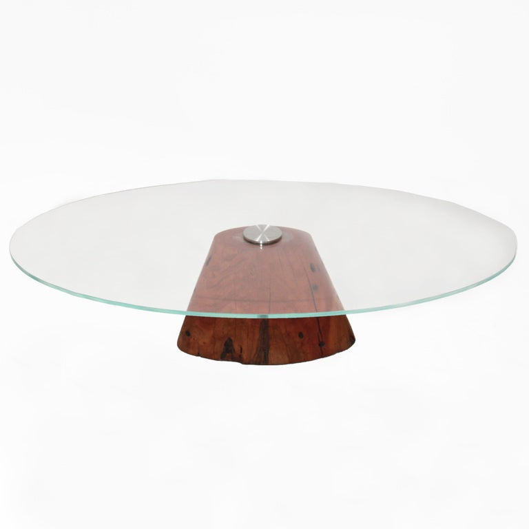 Custom live edge made coffee table by Brazilian designer Tunico T featuring a salvaged chunk of Jatoba wood which has been crafted to make a sturdy plinth base for a thick piece of oval shaped glass to be mounted. The glass is anchored by sturdy