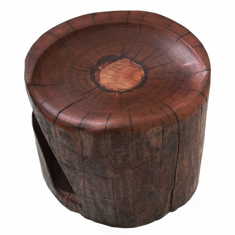A carved, solid Angica Vermelho stool by Tunico T. There is a carved cut-out which could hold papers, etc. Tunico T. lives in Brasilia with his wife and two of his children. He finds his raw materials in the surrounding Cerrado, the largest savannah