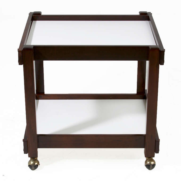 A solid Brazilian exotic hardwood serving cart with chrome wheels and two white melamine shelves. 

 