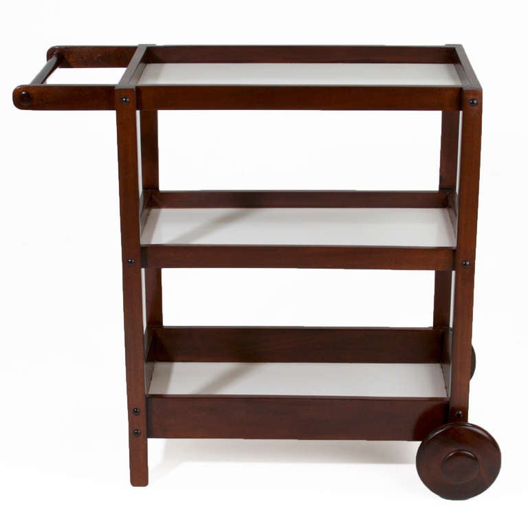 A solid Peroba wood bar cart, tea cart, or serving cart from Brazil with three shelves of white melamine and large round solid wood wheels for easy mobility. 

Many pieces are stored in our warehouse, so please click on CONTACT DEALER under our