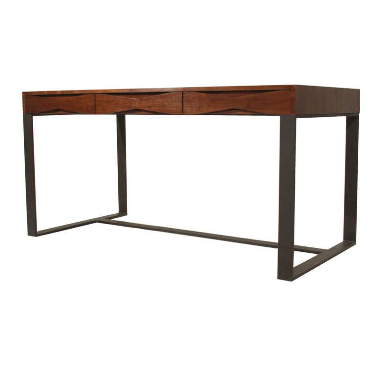 A walnut desk by Thomas Hayes Studio with three drawers with sculptural solid Walnut bow tie details that also acts as pulls. The top sits upon a frame of flat black finished solid steel base. Desk is VERY heavy and sturdy. Drawers have soft close