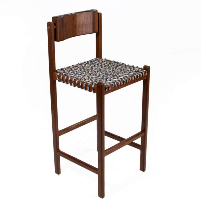 A sturdy solid Walnut stool with a seat of woven multicolored Paracord and back of carved solid Walnut that pivots for ultimate comfort. The frame has brushed brass details on the sides. 

Seat depth: 16