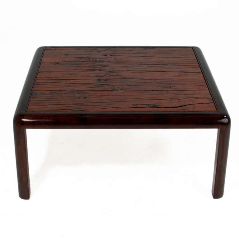 A square Brazilian Ipe wood coffee table with rounded edges and solid legs. The base is solid wood with a dark stained satin lacquer finish. The Ipe was salvaged from vintage railroad planks, and retains nail holes, cracks and variation in grain