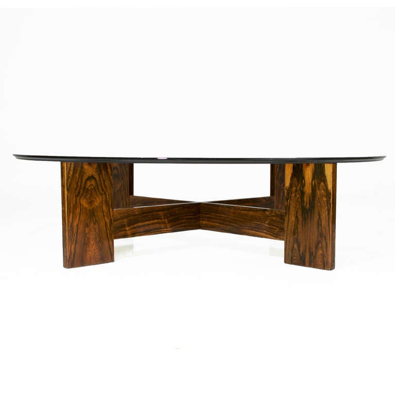 An X-shaped Rosewood base coffee table with glass top from Brazil. The glass top has a beveled edge, and the Rosewood has beautifully graining and some blond sap grain. The glass is original and has some wear, but it can be replaced. The base can