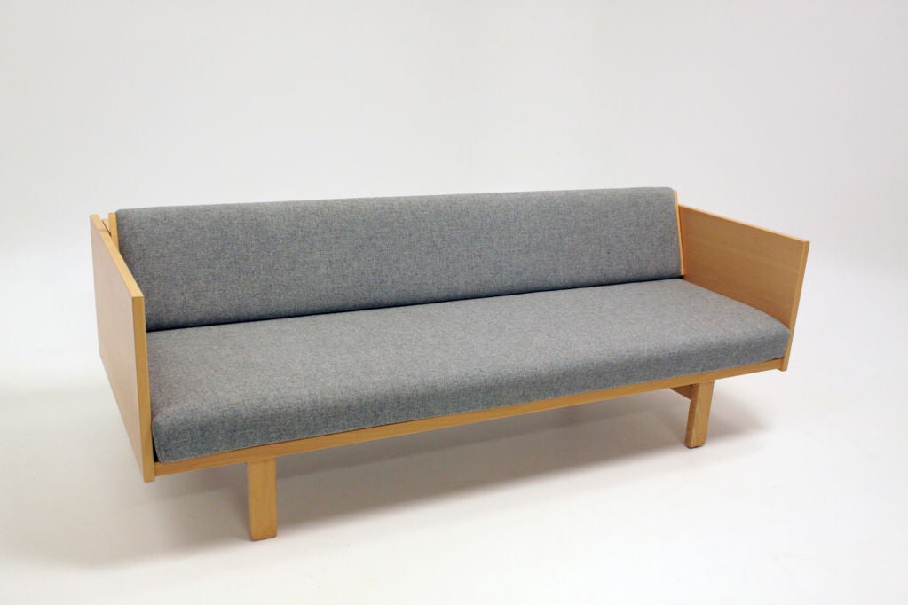 An interesting sofa design by Hans Wegner in birch with blue wool upholstery. The back folds up to make the seat cushion large enough to be a bed. When folded down and in 
