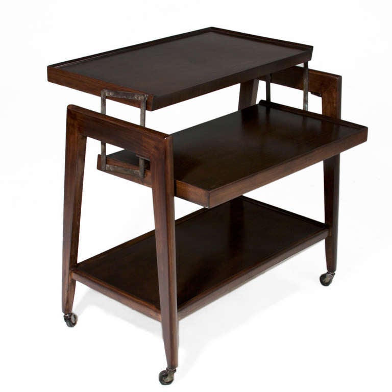 A lovely exotic Brazilian hardwood serving tray or bar cart with a low shelf and an upper shelf that swings up and back to make two upper shelves for serving. The splayed tapered legs have original rolling casters for easily mobility. 

Many