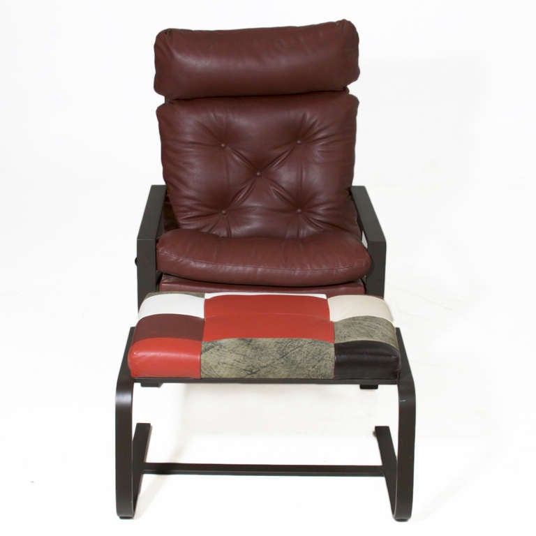 A black iron flat bar arm chair with a high back that reclines and tufted burgundy leather upholstery. The ottoman is upholstered in a contrasting patchwork leather. 

Seat depth: 18.5