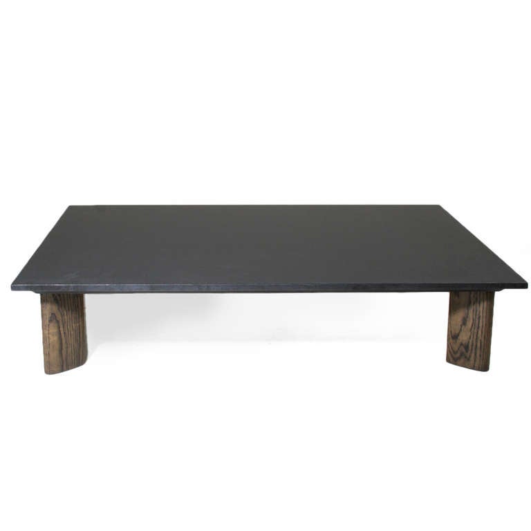A stunning coffee table in Solid Oak with a charcoal oil finish with a honed black granite top. The narrow rectangular legs with rounded edges are each angled towards the inside of the table creating a sculptural look. 

This item is available for