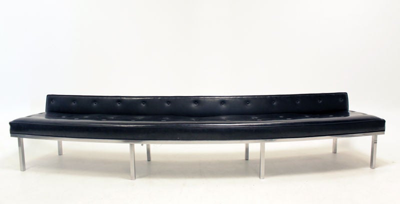 A massive tufted curved low back bench with polished solid Stainless Steel legs in original condition. The sofa comes apart in three sections, the middle portion being the longest. This sofa is extremely heavy as the Stainless is very thick and