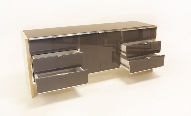 A grey glass and chrome credenza with chrome finished aluminum pulls attributed to Milo Baughman. Bases are a thick bleached oak plinths.
Many pieces are stored in our warehouse, so please give us a call at (323) 463-4434 or email us at