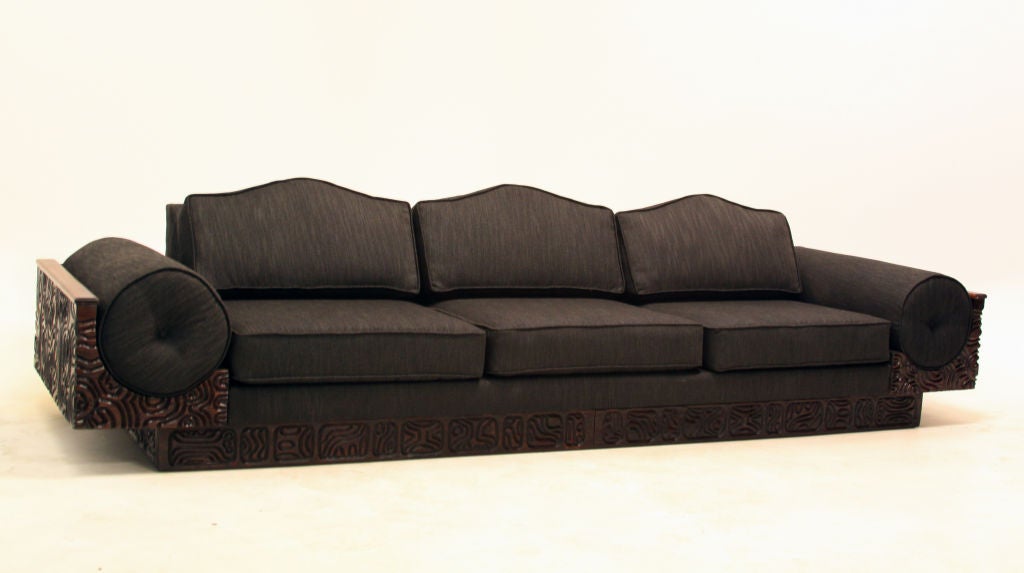 Huge sofa upholstered in a charcoal fabric with round side pillows and intricate carving along laminated redwood base.<br />
Many pieces are stored in our warehouse, so please give us a call at (323) 463-4434 or email us at
