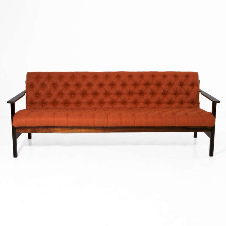 A beautiful Brazilian sofa in solid Rosewood. The Rosewood has been refinished in a satin lacquer and the burnt orange tufted fabric has been newly upholstered. 

Seat depth measures 21