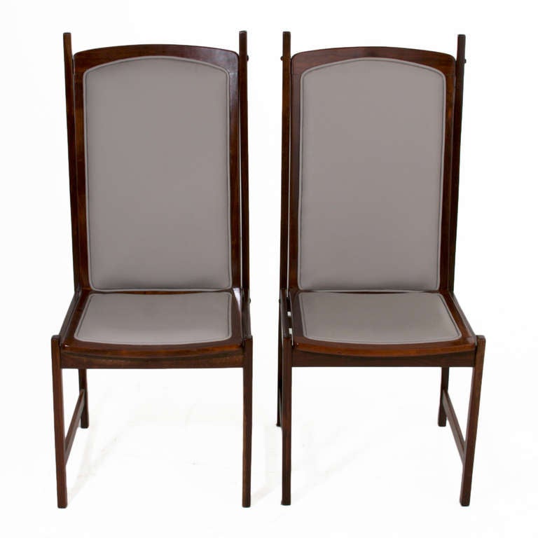 Pair of Brazilian Mogno dining or side chairs with architectural frames by Celina Moveis Decoracoes. These chairs have a constructivist feel with hard angles and intersecting joinery. The chairs have been upholstered with a high quality gray leather