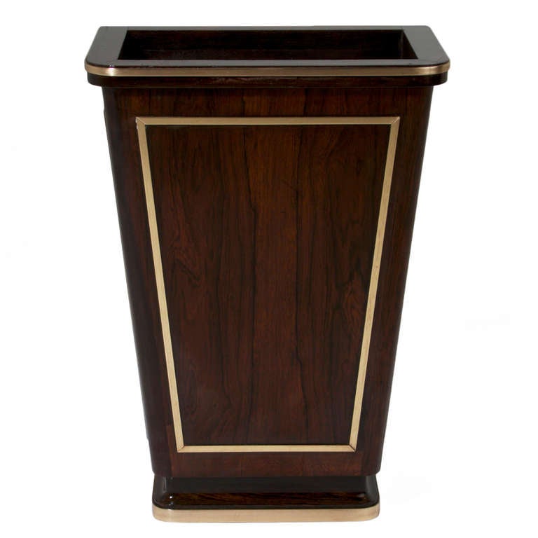 An elegant Brazilian waste basket in solid Rosewood lined with brass trim. The waste basket is meant to be flush against the wall. There are beautiful bronze trimmings along the top, bottom, and all three sides of the piece. 

Many pieces are