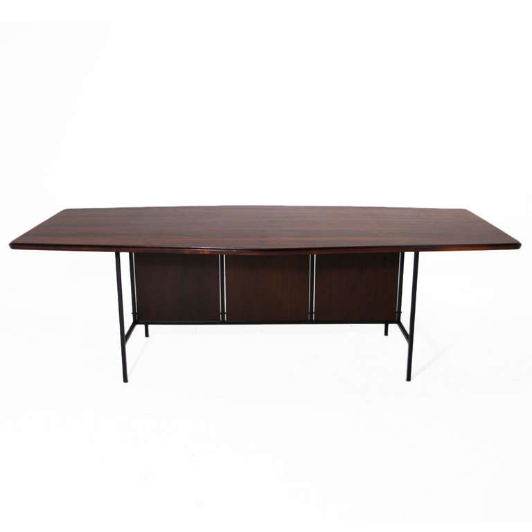 A uniquely shaped exotic Brazilian hardwood dining table with a black iron base. 

