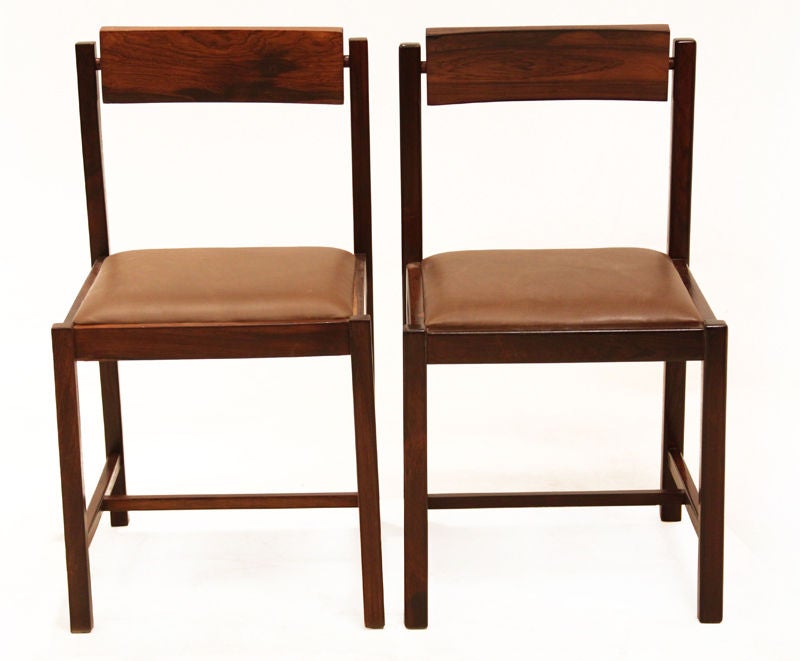 Set of eight solid rosewood dining chairs with significant grain pattern and upholstered brown leather seats. The back of the chairs rotate on a rosewood rod for adjustable comfort. These chairs were designed by Mobilia Contemporanea for Rapoport.