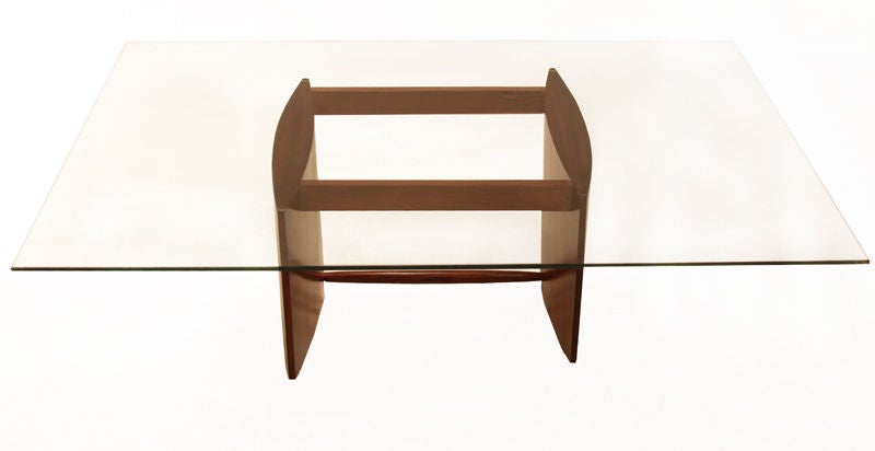 A large glass top rests on an asymmetrical curvilinear Caviuna base. The two bowed side panels are connected by three support beams. Each panel sits on two tapered solid Caviuna legs. Base can support a different sized glass top if needed.