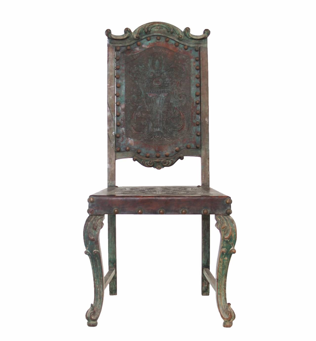 A vintage side chair by Dom Pedro with ornate frame with distressed, rustic brown and green aged finish. The back and seat are embossed original leather. There is one tear in the leather on the top back panel but it can be reinforced from the back