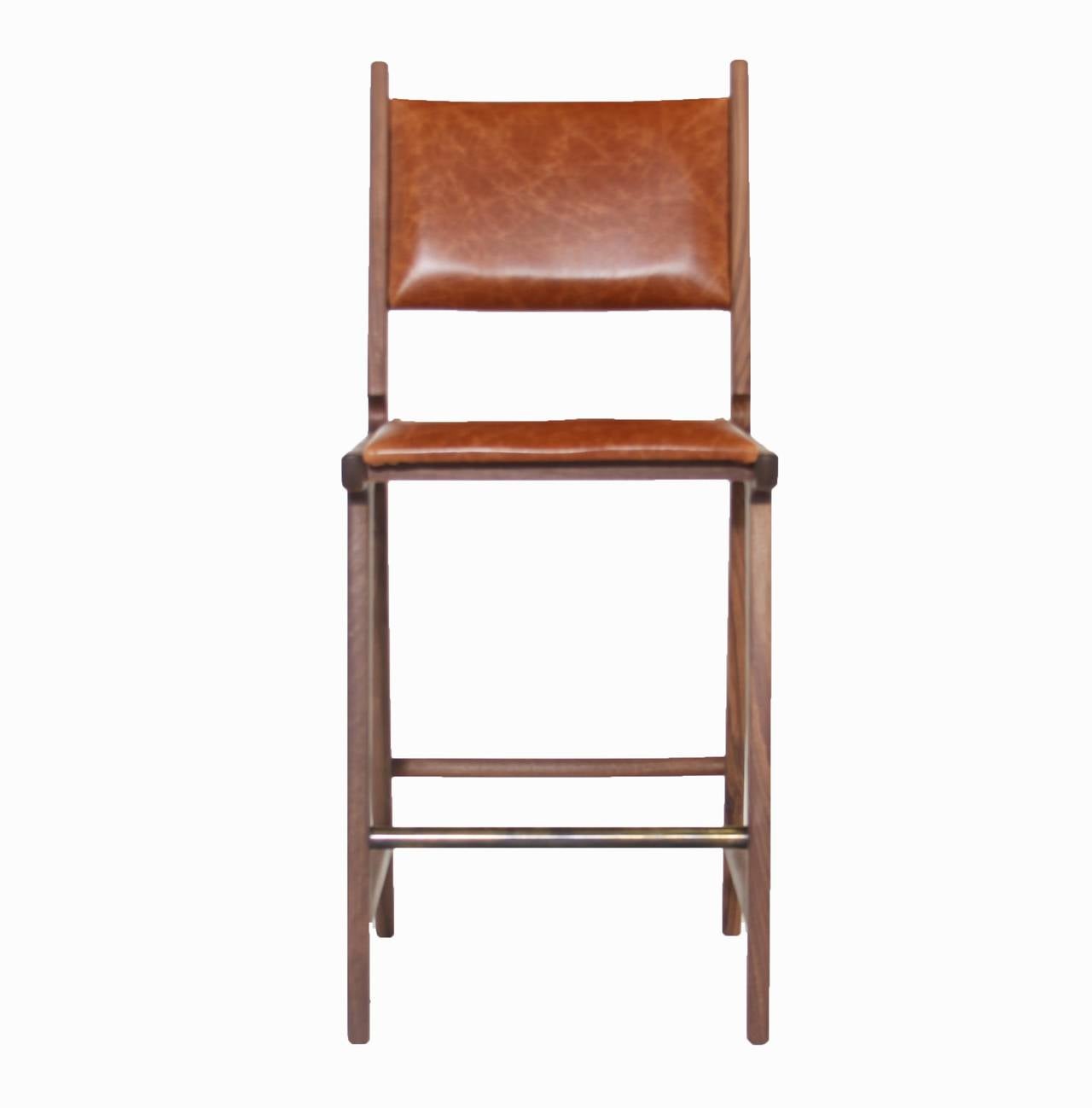 A sculptural bar stool in solid wood available for custom order by Thomas Hayes Studio inspired by the designs of Martin Eisler with comfortable upholstered seat and floating back. The stools have a beautiful detail at the back of the seat frame and