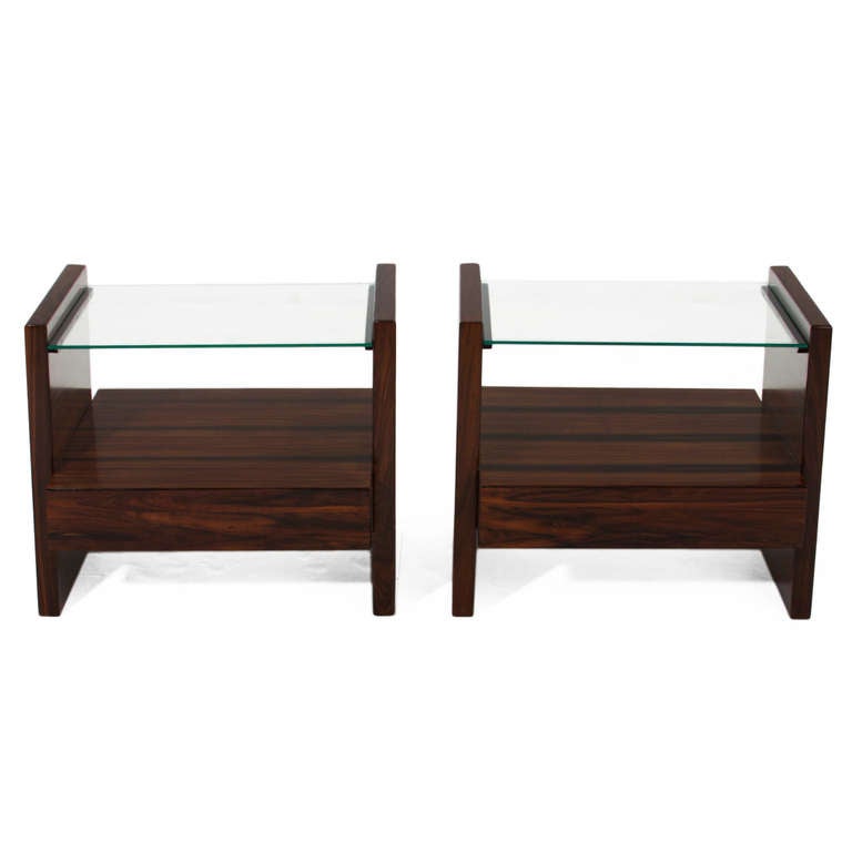 A pair of lovely Brazilian rosewood side tables or nightstands with one drawer a piece and floating glass tops designed by Brazilian company Celina Moveis. The rosewood grain is especially beautiful

Many pieces are stored in our warehouse, so
