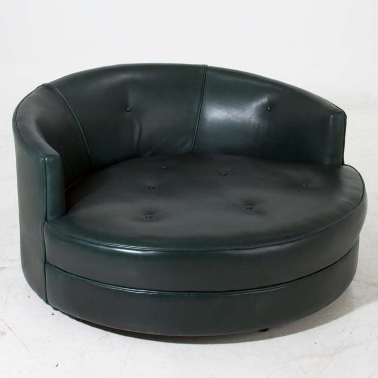 Large round swivel chair upholstered in a high quality green leather with tufted seat cushion and Walnut base. This chair is large enough to comfortably seat two people. Designed by Milo Buaghman for Thayer Coggin. 

The leather has been damaged,