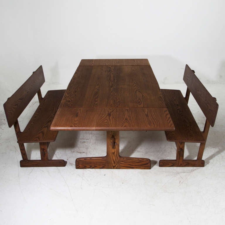 A custom trestle dining table with matching benches made from solid Oak and designed by Gerald McCabe for Orange Crate Modern. The set has been beautifully refinished with a dark oil finish that is durable and almost water proof, is silky smooth to