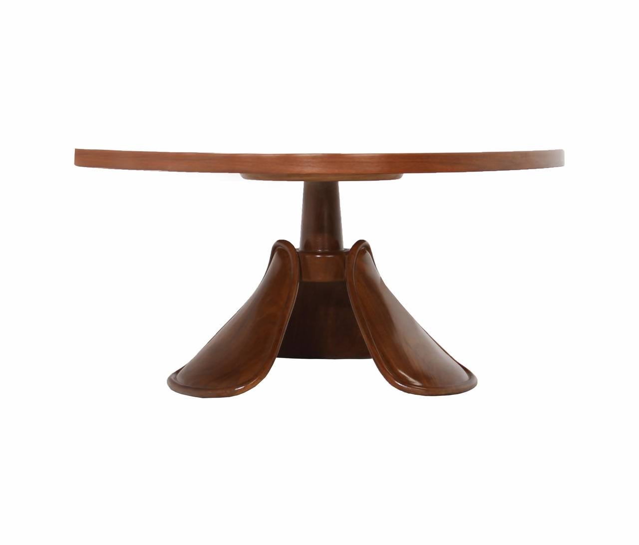 A uniquely shaped California Craftsman rounded triangle top coffee table in Walnut with three sculptural carved Walnut feet with beveled edges. The finish is original and in really good shape with only the most minor blemishes consistent with
