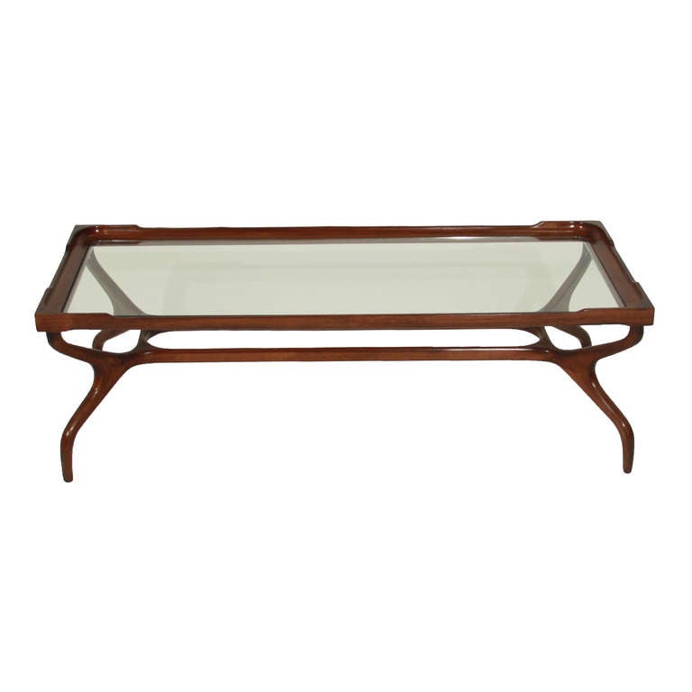 A sculptural glass coffee table by Guiseppi Scapinelli in rich Peroba de Campos. The legs curve inward, connect, and curve outward while tapering toward the base. It is an obviously Brazilian design but also highly influenced by Italian design at