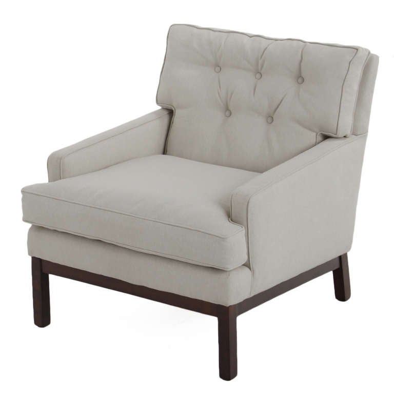 A simple designed Lounge chair and ottoman upholstered in an off-white fabric. The chair back cushion is tufted. The legs on the chair and ottoman are a Walnut finish. 

Many pieces are stored in our warehouse, so please click on CONTACT DEALER