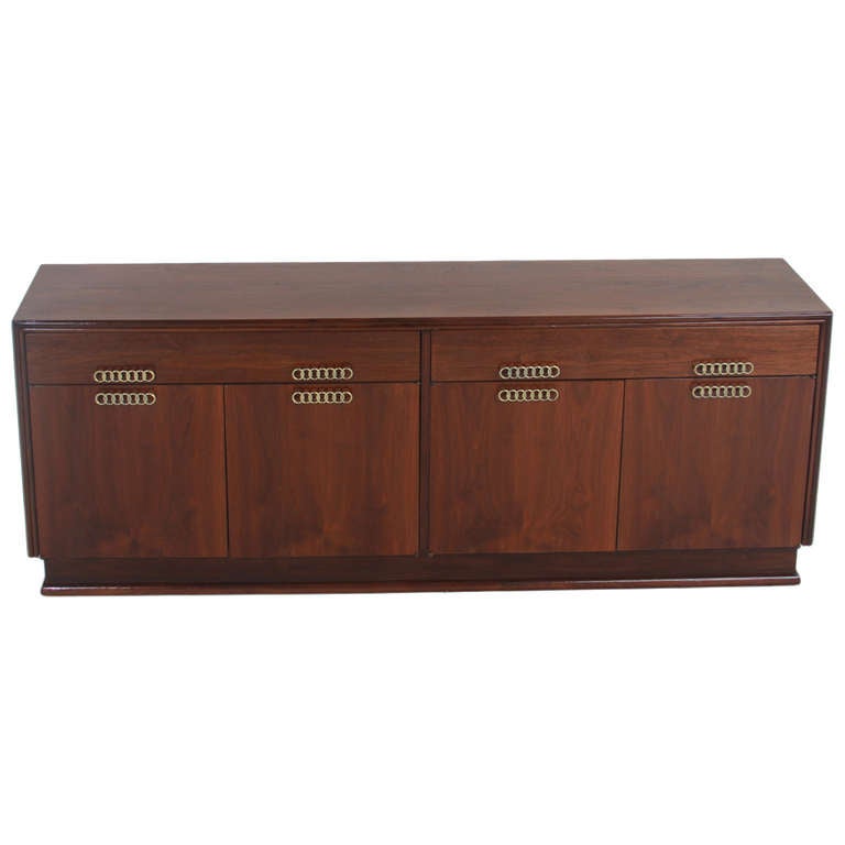 A beautiful walnut cabinet with recessed base, drawers along the top, and original bronze pulls with the patina of age designed by Brown Saltman. 

 