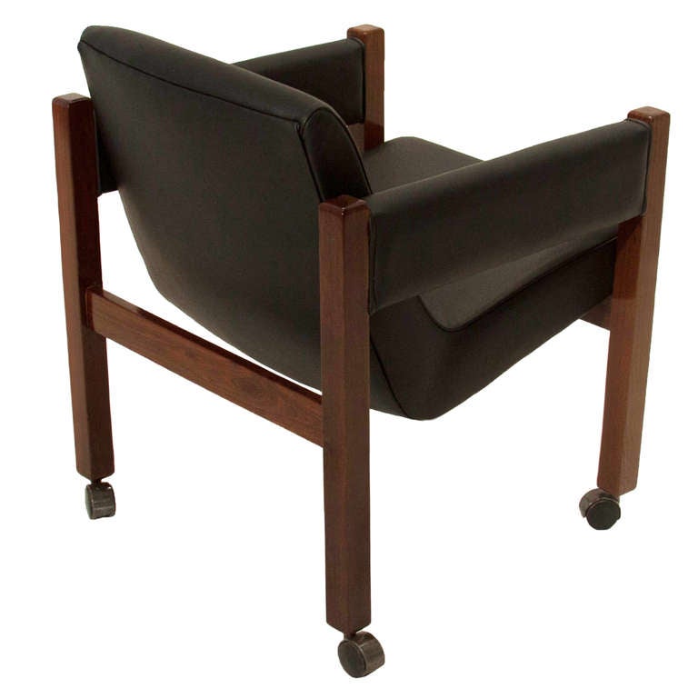 A single comfortable desk chair or side chair on rollers from Brazil in solid Rosewood with seat upholstered in black leather with a row of button tufting, possibly by Sergio Rodrigues. 
Seat depth: 20