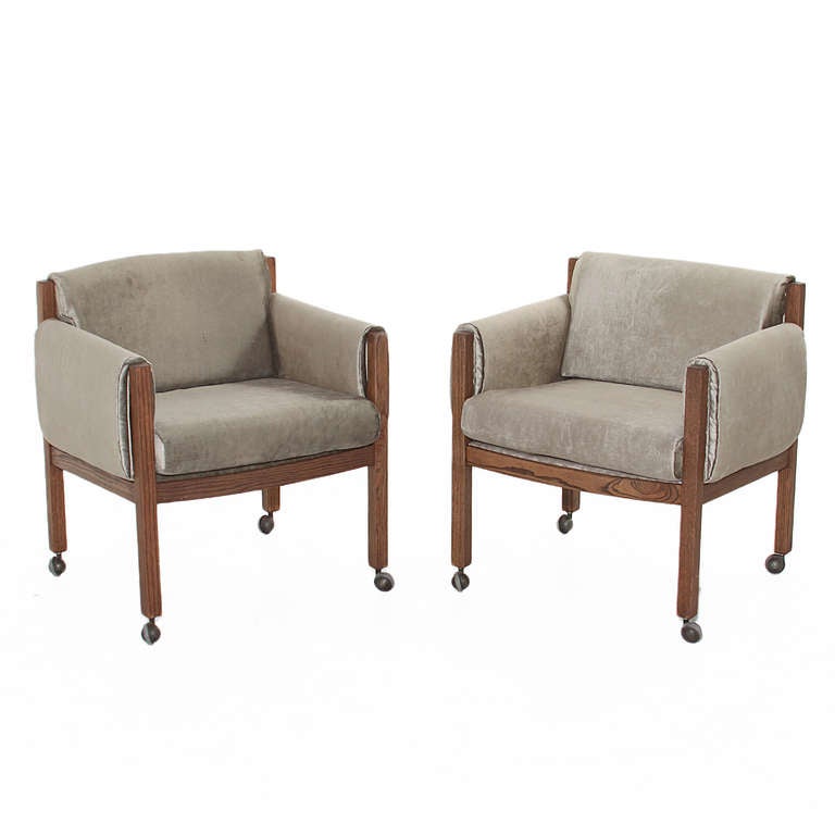A beautiful pair of chairs in solid oak with a chocolate oil finish. The chairs have been upholstered in an elegant grey velvet fabric. The chairs do have wheels attached for mobility. These would be great in an office. 

Measures: Seat depth