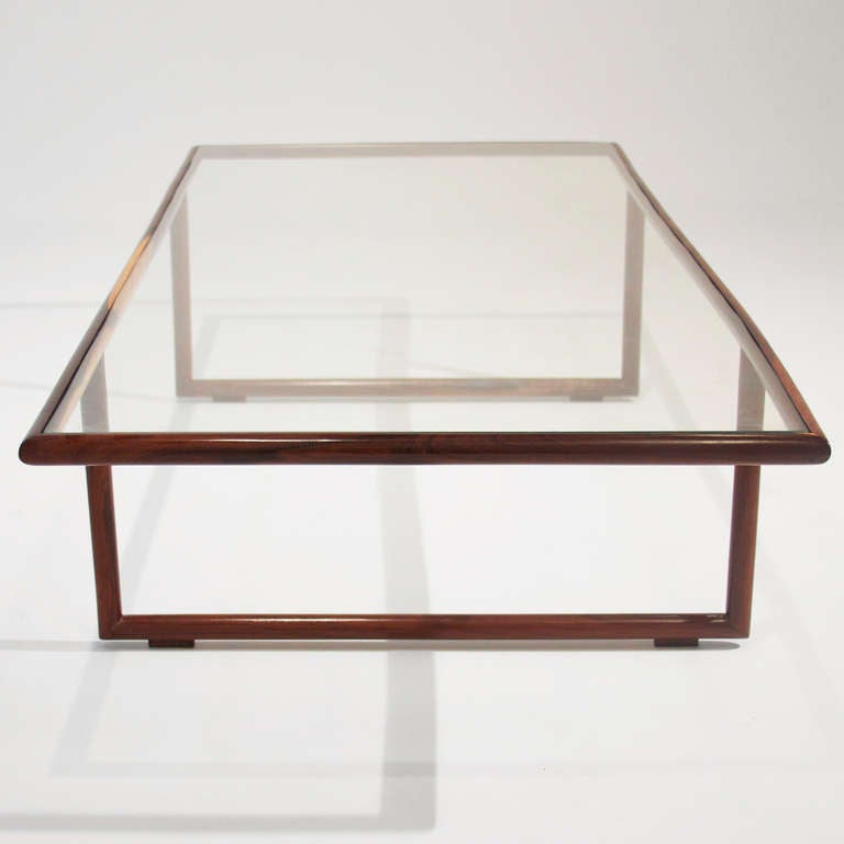 An elegant coffee table by Brazil's Joaquim Tenreiro with solid sculpted Rosewood frame and inset glass top. 

Many pieces are stored in our warehouse, so please click on CONTACT DEALER under our logo below to find out if the pieces you are